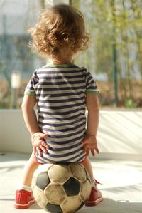 Hochsensibles Kind beobachtet auf einem Fu&szlig;ball sitzen sein Umfeld
