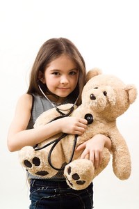 Kind H&ouml;rt mit einem Stetoskop die Brust ihres B&auml;ren ab. Link zu Erster Hilfe am Kind.