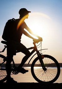 Mann f&auml;hrt bei untergehenden Sonne Fahrrad